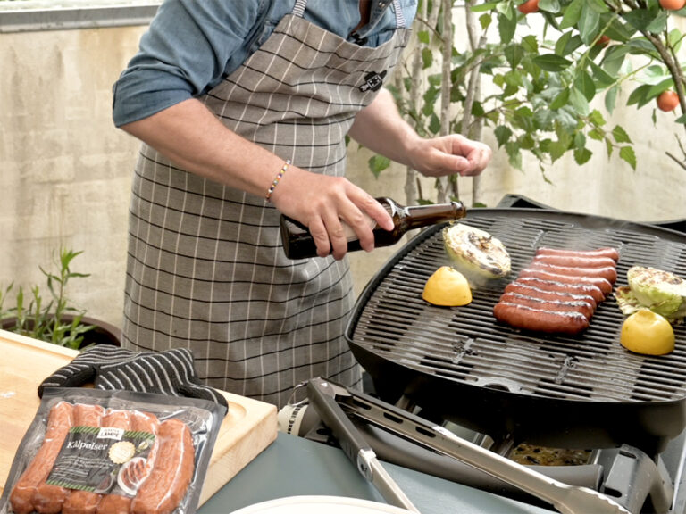 Mand som griller kålpølse og spidskål med øl